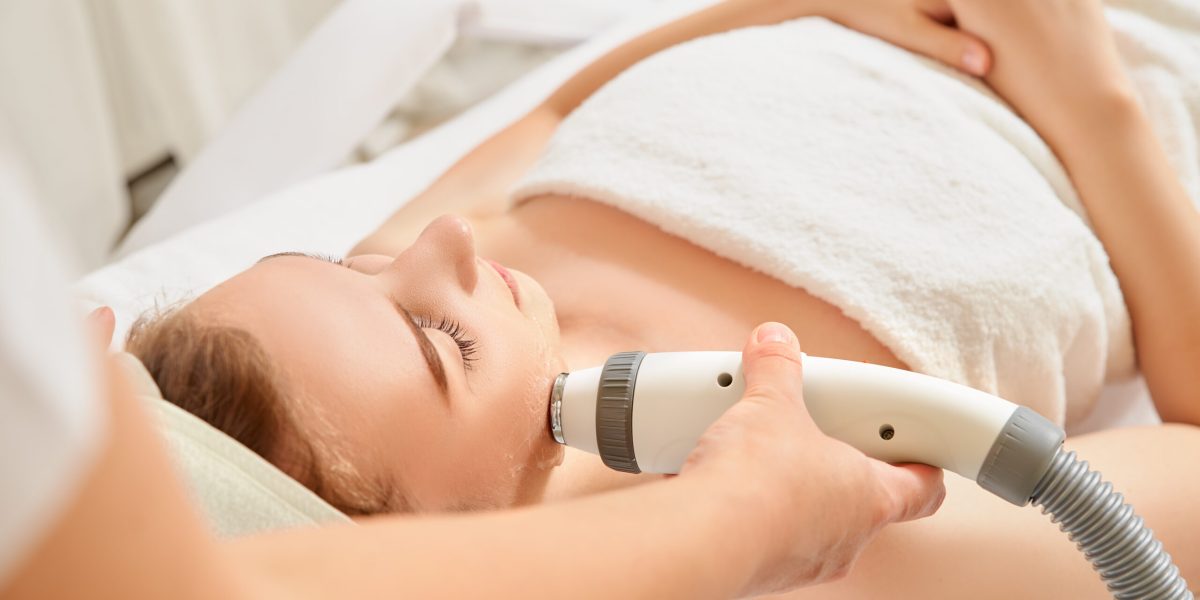 Close-up cosmetologist making ultrasound hardware cleaning of the face of her patient a beautiful young woman. Concept skin cleansing and restoration of elasticity