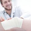 doctor bandaging a wound on the leg of the patient