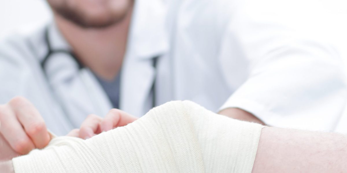 doctor bandaging a wound on the leg of the patient